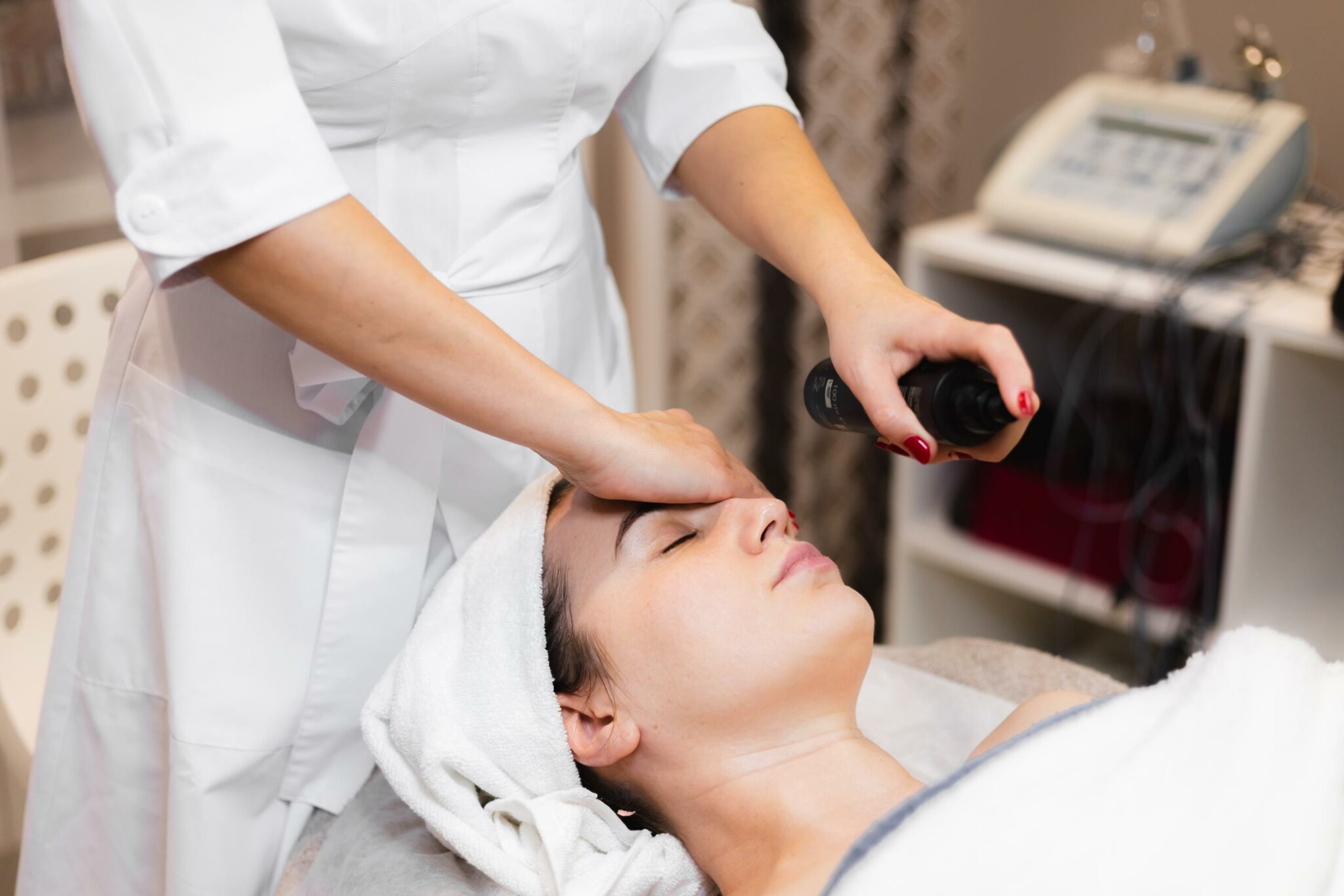 woman client salon receiving manual facial massage from beautician 1